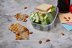 Back to School concept, school supplies, biscuits, packed lunch and lunchbox over white chalkboard, selective focus.