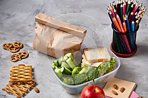 Back to School concept, school supplies, biscuits, packed lunch and lunchbox over white chalkboard, selective focus.