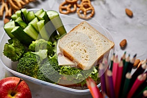 Back to School concept, school supplies, biscuits, packed lunch and lunchbox over white chalkboard, selective focus.