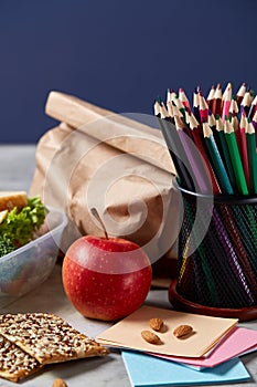 Back to School concept, school supplies, biscuits, packed lunch and lunchbox over white chalkboard, selective focus.