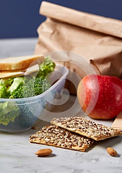 Back to School concept, school supplies, biscuits, packed lunch and lunchbox over white chalkboard, selective focus.