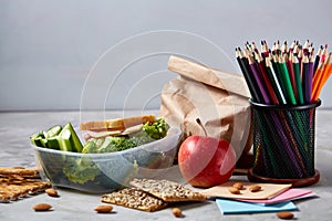 Back to School concept, school supplies, biscuits, packed lunch and lunchbox over white chalkboard, selective focus.