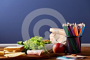 Back to School concept, school supplies, biscuits, packed lunch and lunchbox on white desk, selective focus, close-up.