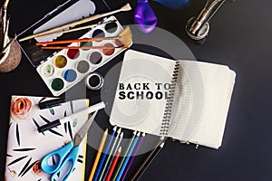 back to school concept text chalk on board, colorful pencils paints brushes scissors and notebook, space for text, flat lay