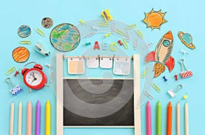 Back to school concept. Top view image of empty blackboard, space ship and student stationery over pastel blue background