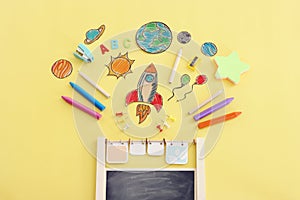 Back to school concept. Top view image of space ship, planets, blackboard and student stationery over pastel yellow background