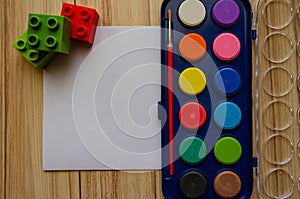 Back to school concept watercolor palet flat lay with blank paper and building blocks