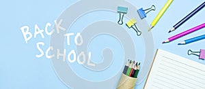 Back to school concept. Wooden colored pencils, clean school notebook in line, paper clips on blue background top view flat lay