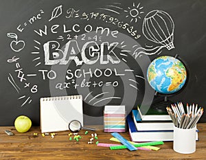 Back to school concept with writing on blackboard and desk, apple, books, stationery.