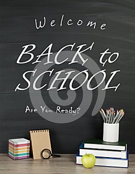 Back to school concept with writing on blackboard and desk, apple, books, stationery.