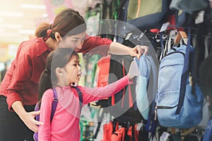 Back to school concept, Young asian mother or parent and little girl kid or cute pupil buying school satchel or bag in store,