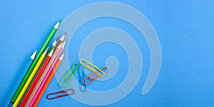 Back to school concepts, colorful pencils and clips for drawing on vibrant blue background