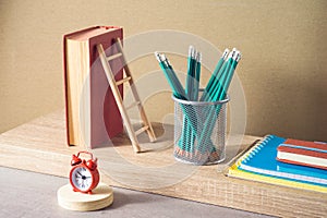 Back to school creative concept with pencils, books and alarm clock. Modern still life composition