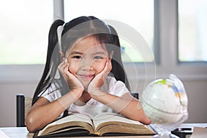Cute asian child girl with a book smiling in the classroom