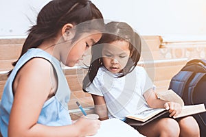 Cute asian child girl and her sister reading a book