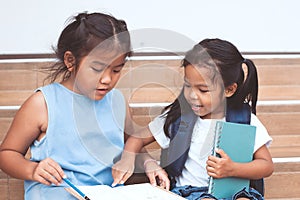 Cute asian child girl and her sister reading a book