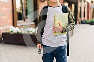 Back to school. Cute child with backpack holding notepad and training books going to school. Boy pupil with bag