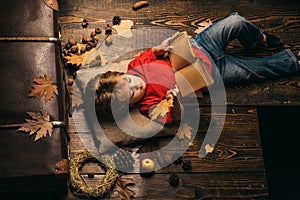 Back to school. Cute little child boy are getting ready for autumn. Little cute boy lies on a wooden floor with autumn