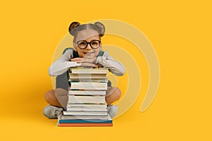 Back To School. Cute Little Schoolgirl Leaning At Book Stack And Smiling