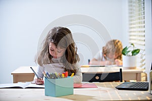 Back to School. Cute pupil writing at desk in classroom at the elementary school. Student girl doing test in primary