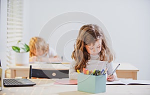 Back to School. Cute pupil writing at desk in classroom at the elementary school. Student girl doing test in primary