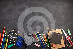 Back To School and education Concept. Alarm clock, color chalk and over supplies on blackboard background. Copy Space, top view