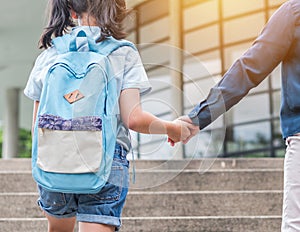 Back to school education concept with girl kid elementary student carrying backpacks holding parent woman or mother`s hand