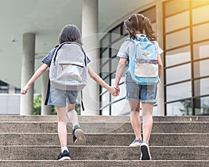 Back to school education concept with girl kids elementary students carrying backpacks going to class