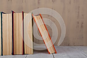 Back to school and education concept  heap colorful hardback books on white wooden table on brown background