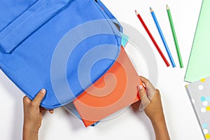 Back to school, education concept. Kid hands packing backpack and preparing for school