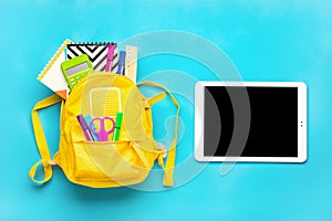 Back to school, education concept. Yellow backpack with school supplies Notebook, pens, ruler, calculator, scissors, tablet