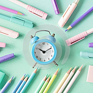 Back to school, education and work concept. Stationery for learning (study) and alarm clock on mint background.