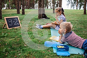 Back to school. Elementary scholars sitting on the grass during their open air class