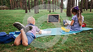 Back to school. Elementary scholars sitting on the grass during their open air class