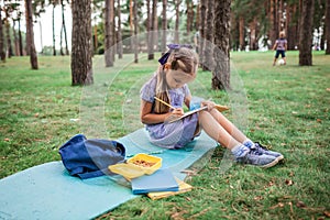 Back to school. Elementary scholars sitting on the grass during their open-air class