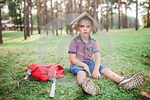 Back to school. Elementary school kid sitting on green grass with book at open-air class