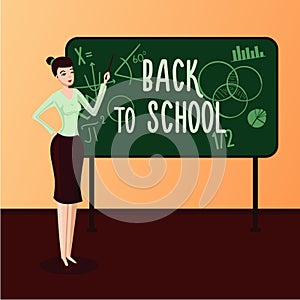 Back to School. Female teacher in a classroom standing near chalk board.
