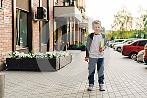 Back to school. Funny child with backpack holding notepad and training books going to school. Boy pupil with bag