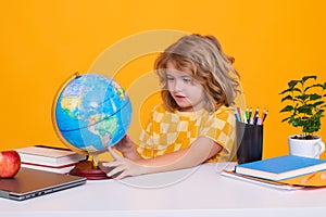 Back to school. Funny little boy from elementary school looking at globe during geography lesson. Education.