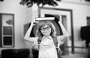 Back to school. Funny little boy in glasses at school. Child from elementary school with book and bag. Education child.