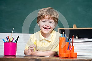 Back to school. Funny little kid pointing up on blackboard. Cute little preschool kid boy in a classroom.