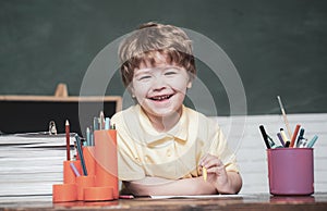 Back to school. Funny little kid pointing up on blackboard. Cute little preschool kid boy in a classroom.