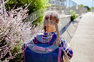 Back to school. Girl with backpack goes to school at the first day after vacation
