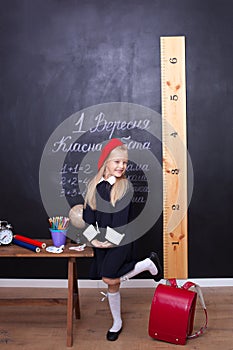 Back to school! The girl at school stands near the board. School concept. Schoolgirl answers at a lesson. On the chalkboard in Ukr