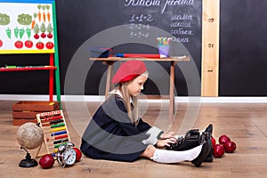 Back to school! A girl sits on the floor at school and holds a retro typewriter. School education. On the blackboard in the Ukrain photo