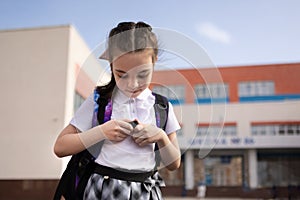 Back to school. Girl in uniform with parent go to school with backpack behind their backs. Beginning of lessons. First