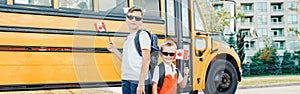 Back to school. Happy Caucasian boys students holding waving Canadian flag. Students kids by yellow school bus outdoor. Education