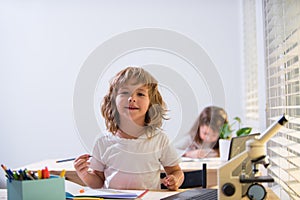 Back to school. Happy cute child is sitting at a desk indoors. Cild is learning in class.