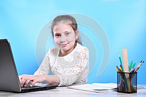 Back to school .Happy cute industrious child is sitting at a desk indoors. Kid is learning in class in home with laptop, computer