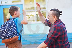 Back to school.Happy father and son are welcome before elementary school. parent meets a child from elementary school.The student